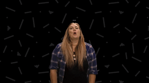 Video gif. Woman in a blue plaid shirt swoops her arms out in an exaggerated way smiles and says, "Welcome to ur 40s!'