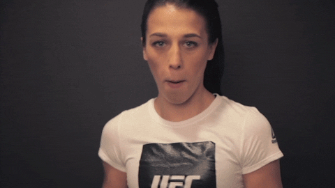 Sports gif. UFC fighter Joanna Jedrzejczyk looks at us and moves her open hand out like she’s giving us a high five through the screen. She makes sound effects with her mouth. 