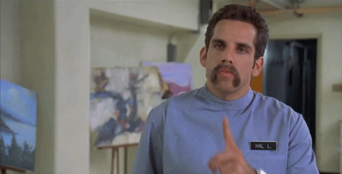 Movie gif. Ben Stiller as Hal in Happy Gilmore brings his index finger to his mouth and across his neck in a threatening, silencing gesture. 
