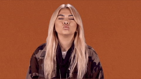 Celebrity gif. Hayley Kiyoko closes her eyes and gives us a bunch of kisses.