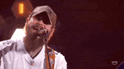 ACM Awards gif. Post Malone sings into microphone briefly twitching head from side to side. 