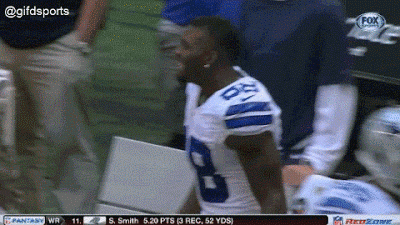 Sports gif. Dex Bryant in a Dallas Cowboys jersey walks on the sidelines and starts fist bumping, patting backs, and dabbing people up. He then walks towards someone and yells at them like he’s pumped up and trying to motivate him.
