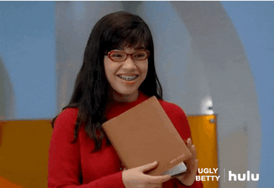 TV gif. America Ferrera as Betty in Ugly Betty. She grins happily while giving us a thumbs up, which she puts close to her face.