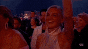ACM Awards gif. Woman in pink halter mock neck bears a happy expression with one arm raised as she vibes to the live performance.