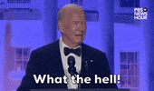 Video gif. President Joe Biden stands behind a podium at the 2024 White House Correspondents' Dinner. He raises his eyebrows nonchalantly and jovially says "What the hell!"