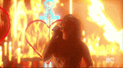Celebrity gif. Kacey Musgraves is performing on stage at the 2021 VMAs and she hits a high note as flames fly out behind her.