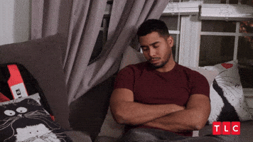 Video gif. A man leans abc on a couch with his arms folded. He shakes his head disappointedly and then leans forward. He hangs his head low and rubs his hands through his hair in distress. 