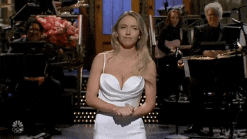 SNL gif. Sydney Sweeney stands on a stage wearing a white dress as she shrugs and shakes her head in confusion, saying, "I've never met her."