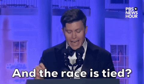 Video gif. Saturday Night Live's Colin Jost stands at a podium at the 2024 White House Correspondents' Dinner as incredulously yells "And the race is tied?"