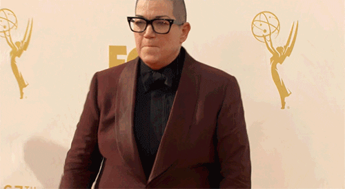 Celebrity gif. Lea Delaria from Orange Is The New Black triumphantly pumps her fist towards the ground and yells in celebration at the Emmys' red carpet.