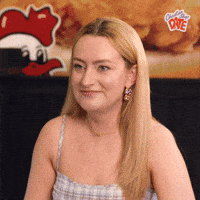 Video gif. Amelia Dimoldenberg, host of Chicken Shop Date, slightly cocks head to the side and raises eyebrows as she lightly smiles.