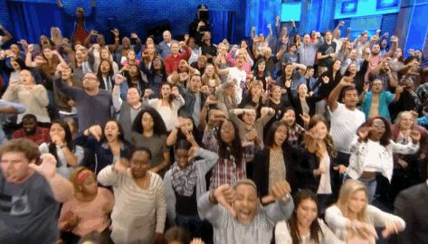 Reality TV gif. The audience at The Maury Show are all standing up and are booing the stage.