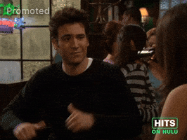 Sponsored GIF. Josh Radner is sitting in a bar talking to a friend, mid conversation he takes a beat to focus the attention on himself by leaning back, pointing his two thumbs back at himself and comedically proclaims himself “this guy” as if delivering a punch line from a joke