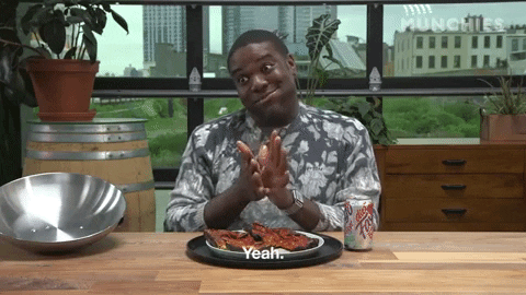 Celebrity gif. Smiling and nodding with a mouthful of food, Sam Richardson rubs his hands over a half-eaten plate of pizza and says, “Yeah.”