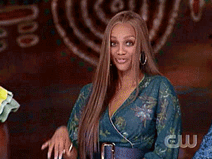 Celebrity gif. An excited and goofy Tyra Banks waves her hand, “hello.”