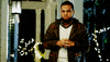 Video gif. A man glances down at his wrist watch and then taps his fingers together impatiently. 