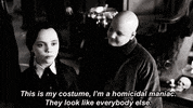 Movie gif. Christina Ricci as Wednesday Addams in The Addams Family says, “This is my costume, I’m a homicidal man. They look like everybody else.” While she says this, Jimmy Workman as Pugsley dressed as Uncle Fester looks at her sister with a smile.