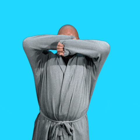 Video gif. Heavyset man in a gray robe yawning wide and stretching his arms above his head. The text, "Yawn" emerges from his mouth against a bright blue background. 