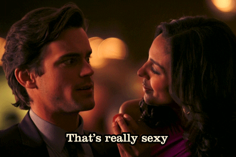 Celebrity gif. Donning a suit and tie, Matt Bomer raises his eyebrows at a woman feeding him a strawberry and says, "That's really sexy."