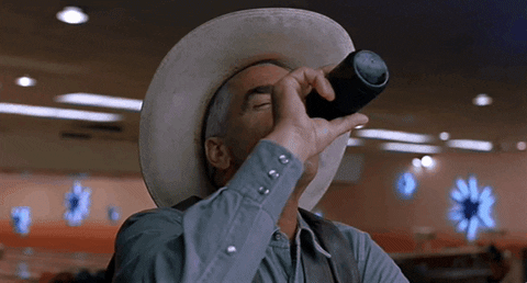 Movie gif. Sam Elliott in The Big Lebowski, wearing a button-down shirt, vest, and white cowboy hat, drinks a bottle of beer, sets it down, swallows, raises his eyebrows and says "thank you."