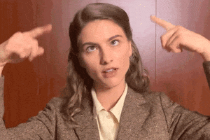 Video gif. A woman rolls her eyes and tilts her head. She spins her fingers nonsensically to the side of her head.