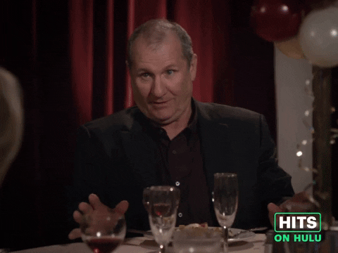Sponsored GIF. Ed Harris sits at a party table where this some awkard tenstion. He attempts to reassure while nodding and saying to the other dinner guests at the table, "I'm having a great time tonight."