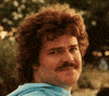 Movie gif. Jack Black as Ignacio in Nacho Libre looks towards the camera with a small, tight grin, and then looks away awkwardly, pressing his lips against his teeth. 