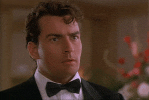 Movie gif. Charlie Sheen as Topper in Hot Shots wears a tux. Steam comes out of his collar as he looks entranced at something. He reaches up to adjust his collar as he swallows uncomfortably. 