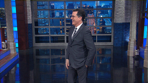 TV gif. Stephen Colbert on the Late Show sticks his tongue out as he outstretches both arms and gives a double thumbs up.