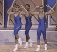 Video gif. Grainy footage shows three men in blue singlets dancing in unison. They snap their fingers, spin and pump their arms before looking up with sunglasses on. Text, "Deal with it." 