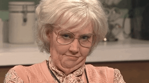 TV gif. Comedian Kate McKinnon as 85 year old Louise from SNL in prosthetic aging makeup seductively winks at us through grandma-style glasses.