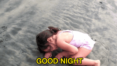 Video gif. Young girl in a pink swimsuit at the beach curls up wearily on the wet sand, as if it's a bed, and tiredly rests her head on her arm. Text reads, "Good Night."
