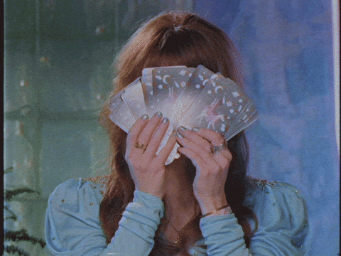 News Sebrae - Edição 56 - GIF de mulher segurando um leque de cartas místicas e tapando o rosto.