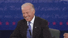 Political gif. Joe Biden sits in a chair during a presidential debate. He shakes his head while laughing. He’s laughing so hard he has his eyes closed and he’s smiling from ear to ear.
