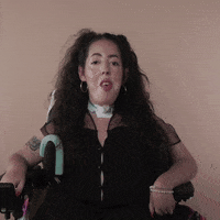 Reaction gif. A Disabled white woman with muscular dystrophy with wavy brown half up half down with two pigtails on top, seated in her motorized wheelchair, rolls her eyes all the way around.