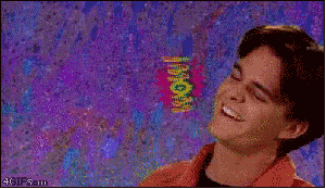 Video gif. A 90s era shot and font of a young man smiling and tilting his head as the text, "Wow," spins out behind him.