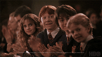 Movie gif. Daniel Radcliffe as Harry, Rupert Grint as Ron, and Emma Watson as Hermione in Harry Potter sit in a row and turn toward us as they applaud happily.