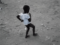 Video gif. Small child dances in a circle, moving his arms stiffly in front of him and behind his back.