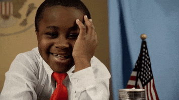 Celebrity gif. Kid President leans on his desk and props his head up with his hand as he giggles shyly.