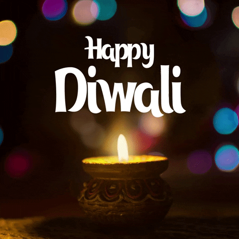 Video gif. Closeup of a small candle with twinkling lights filling the blurred background. Text, "Happy Diwali."