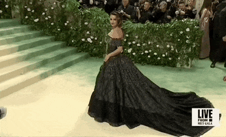 Met Gala 2024 gif. Penelope Cruz wearing a dark custom Chanel Couture off-shoulder gown, poses on the carpet.