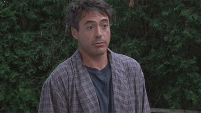 Movie gif. Robert Downey Jr. as Principal Gardner in Charlie Barlett shrugs indifferently in his pajama robes.