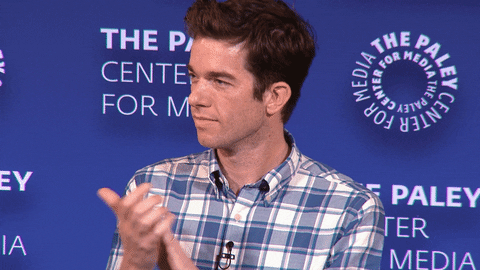 Celebrity gif. John Mulaney applauding respectfully and looking around at PaleyFest 2018.
