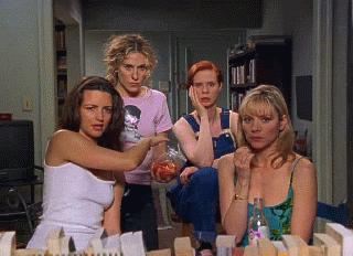 TV gif. Kristen Davis as Charlotte on Sex and the City reaches into a snack bag held by Sarah Jessica Parker as Carrie, standing with Kim Cattrall and Cynthia Nixon as Samantha and Miranda, all staring at us, transfixed.