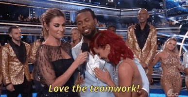 TV gif. Erin Andrews on Dancing with the Stars congratulates two hugging contestants and says, “Love the teamwork!”