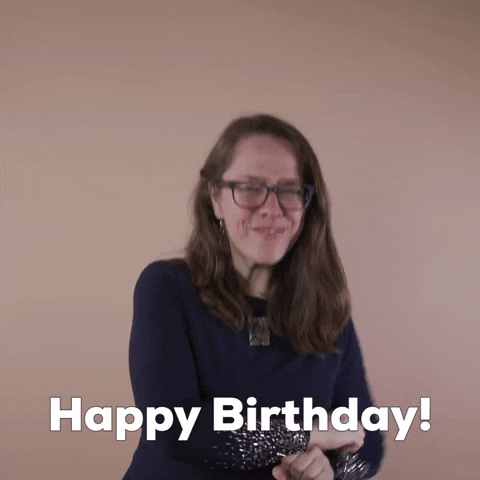 Reaction gif. A Disabled Latina woman with brown wavy hair and glasses smilingly explodes her jazz hands outward, shouting emphatically "Happy birthday!"