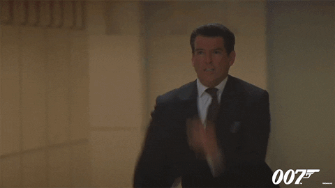 Movie gif. Pierce Brosnan as James Bond in The World Is Not Enough. He's frantically running through a crowd as he yells, "Stop!"