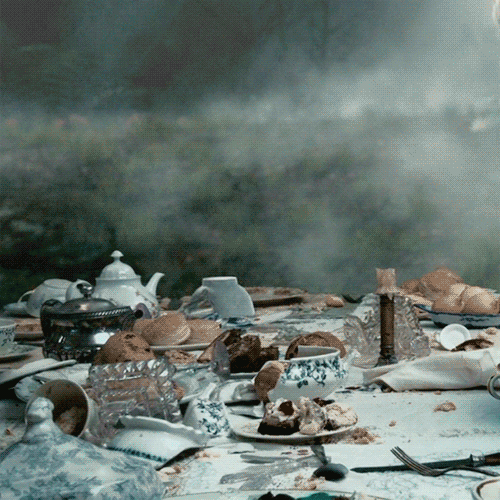 Movie gif. We see a decrepit tea party in Alice in the Wonderland and a teacup floats up. Suddenly, the Cheshire Cat appears and grabs the tea cup perfectly, giving us a sinister smile as they catch it. 
