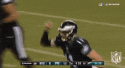Sports gif. Carson Wentz in an Eagles football uniform holds his hand on his helmet and sprints down the field.