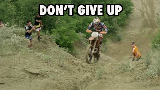 Sports gif. A motocross rider is covered in dirt and is trying to get past a hill. He guns the engine but it stalls out and the bike falls, bringing the rider down with it. Text, "Don't give up!"